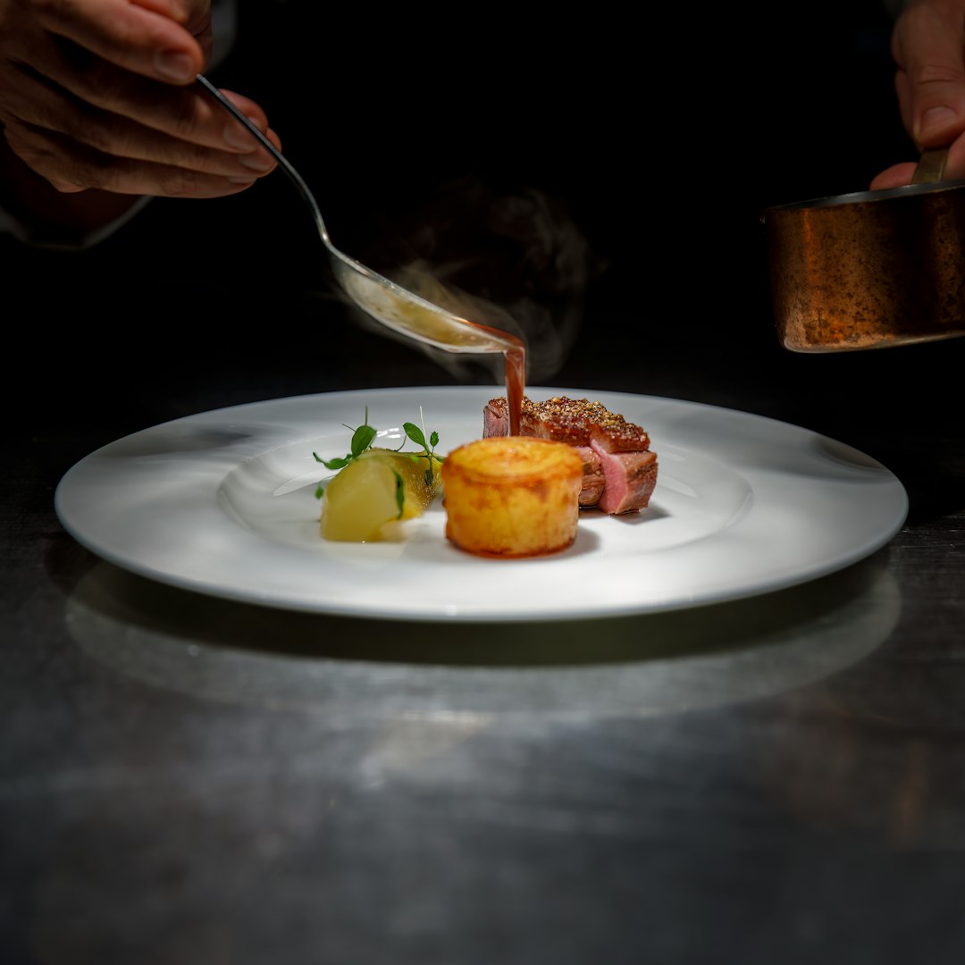 Chef pouring sauce over a plated dish